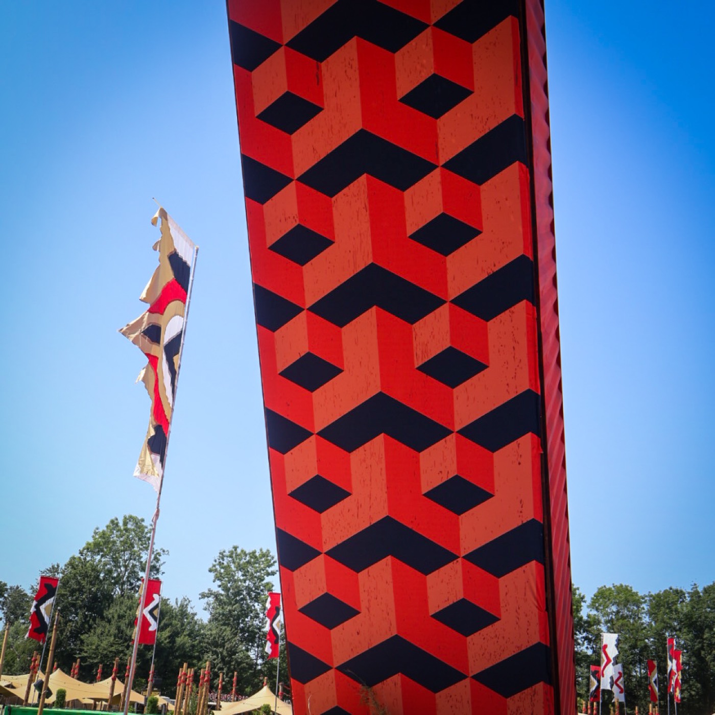 Decorzuil met rood-zwart geometrisch patroon tegen een blauwe lucht