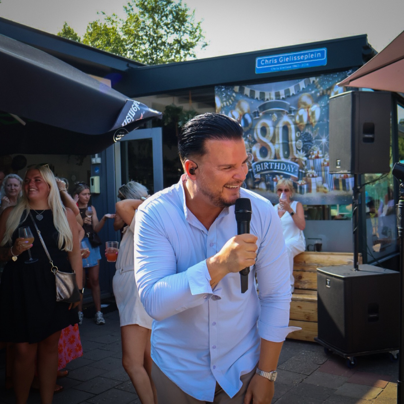 Mike Peterson lacht breed en buigt met microfoon naar het publiek