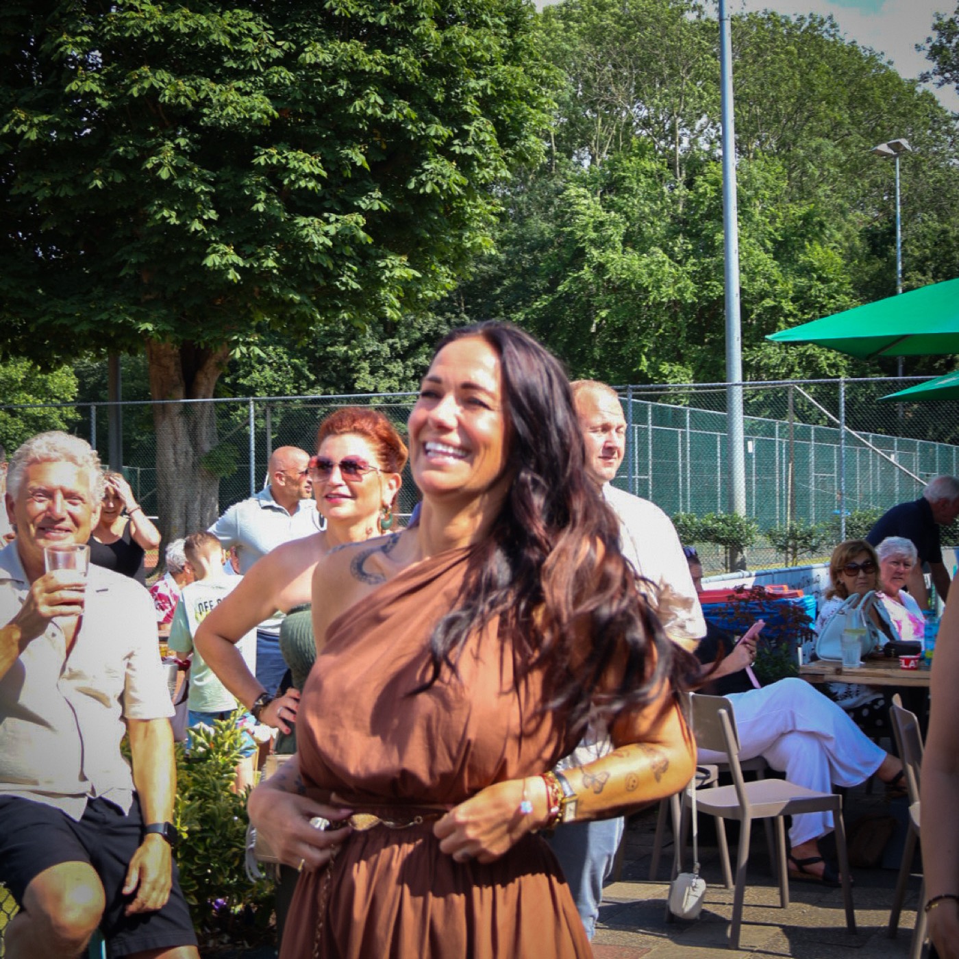 Lachende vrouw in bruine jurk danst vooraan in het publiek tijdens een optreden