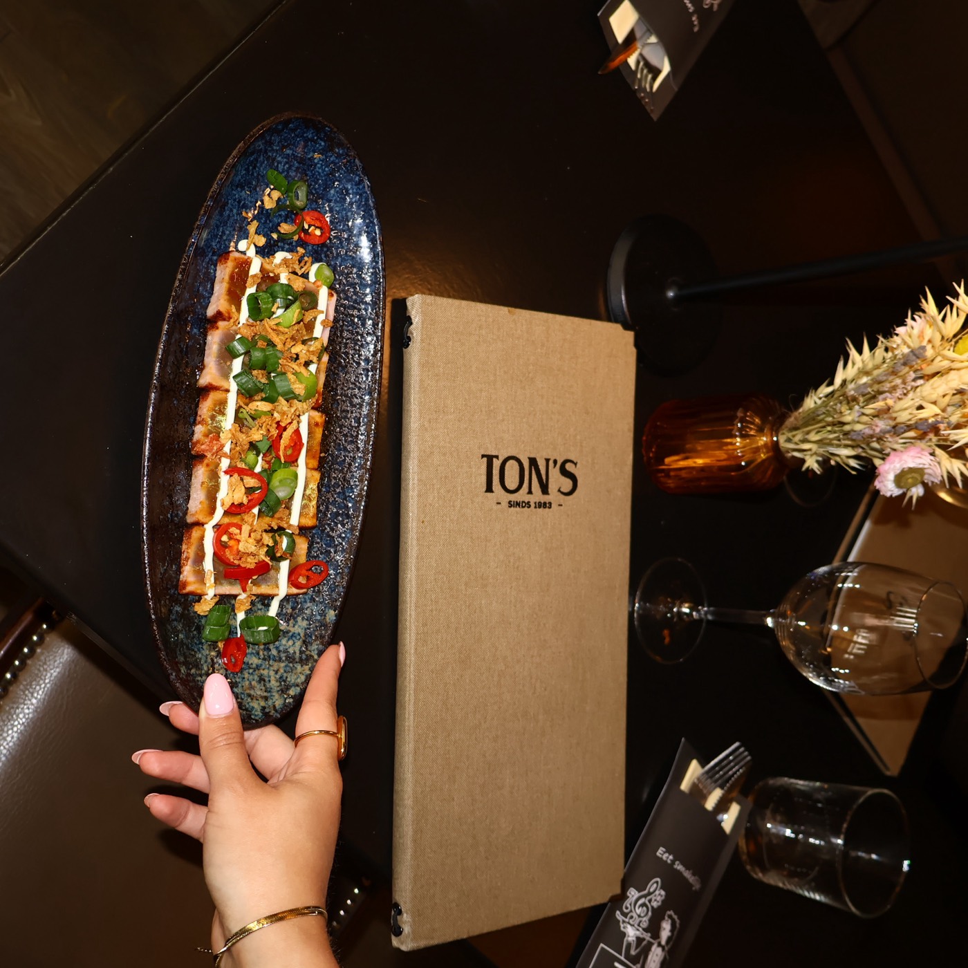 Ovale schaal tonijntataki naast de linnen menukaart van Ton's