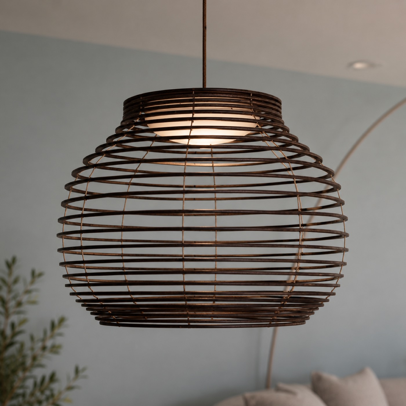 Rotan hanglamp met warm brandend licht voor een zachtblauwe wand